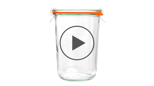 Высокая стеклянная консервационная банка Weck с оранжевой уплотнительной резинкой и металлическими зажимами, вытисненным логотипом Weck на передней стороне, на белом фоне.