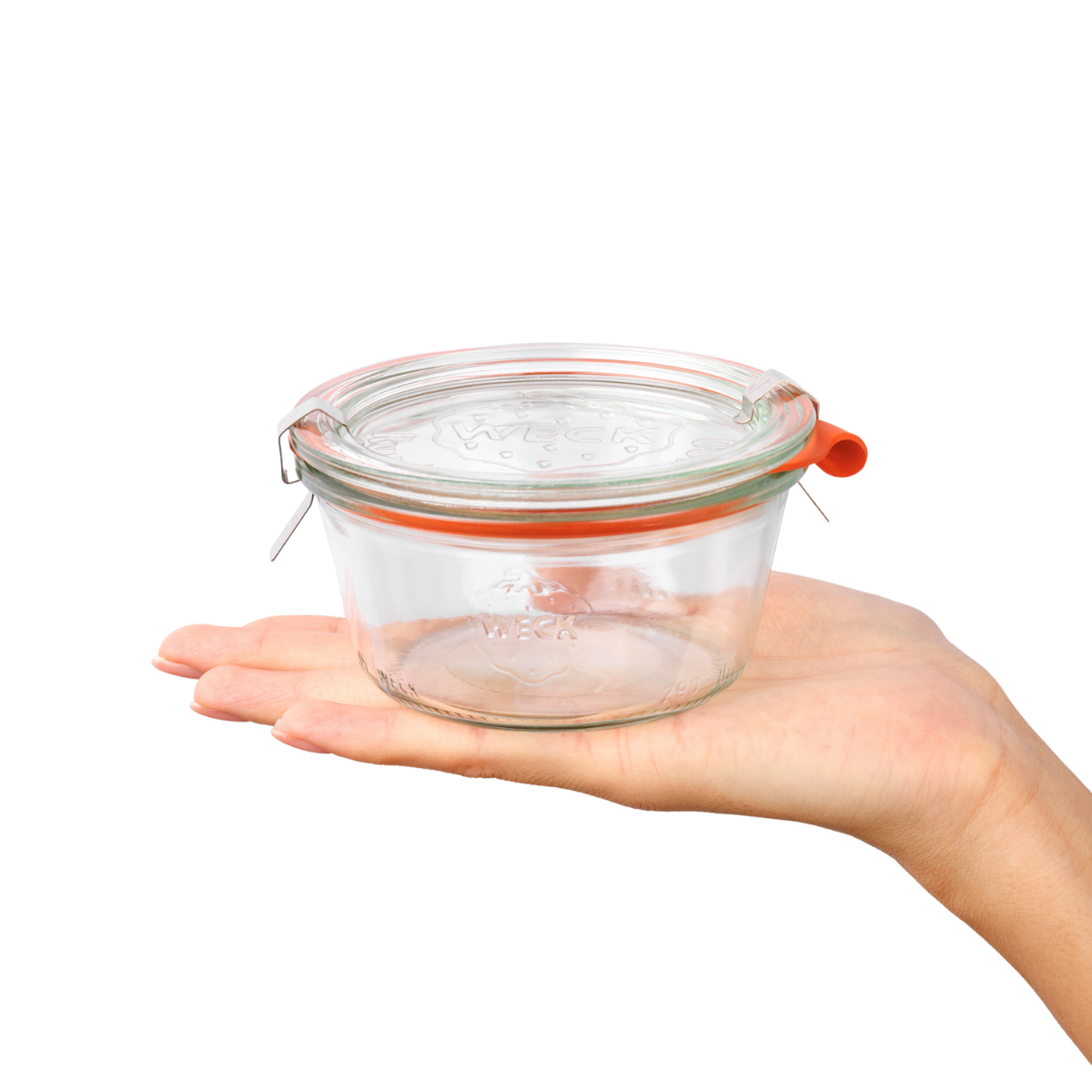 Прозрачная стеклянная баночка Weck с качественной гравировкой и оранжевой застежкой в руке, подчёркивающая надёжность и универсальность использования для хранения продуктов.