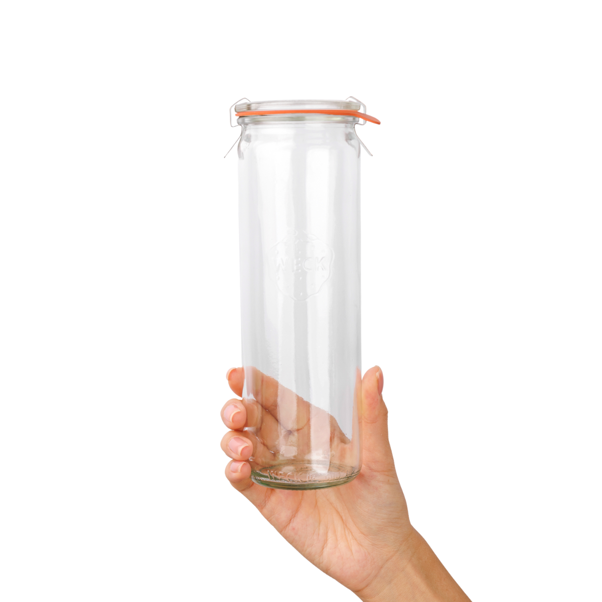 Рука держит высокую цилиндрическую стеклянную банку WECK с оранжевой уплотнительной резинкой и зажимами, гравировка логотипа на белом фоне.