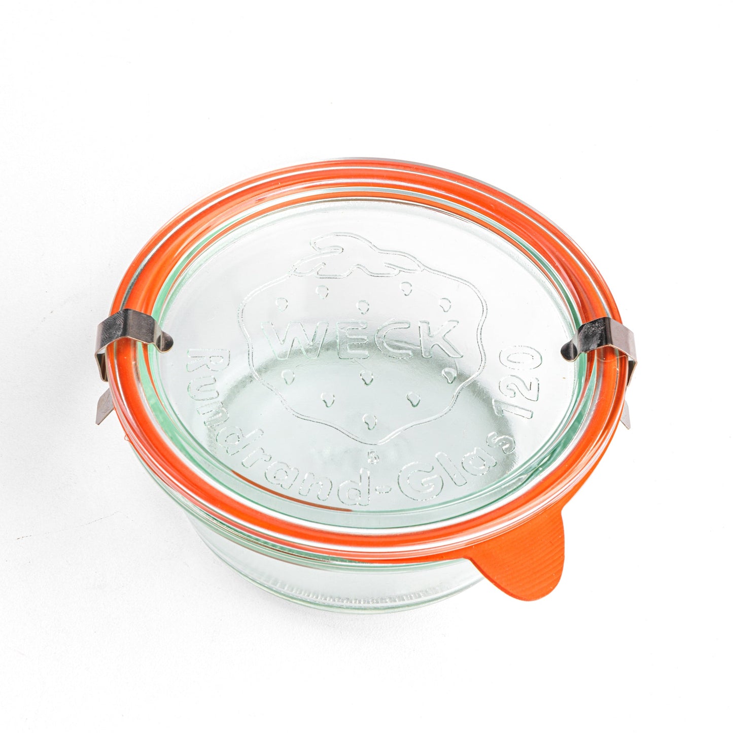 Вид сверху на круглую стеклянную банку Weck с прозрачной крышкой с гравировкой логотипа Weck, оранжевым силиконовым уплотнителем и металлическими зажимами.