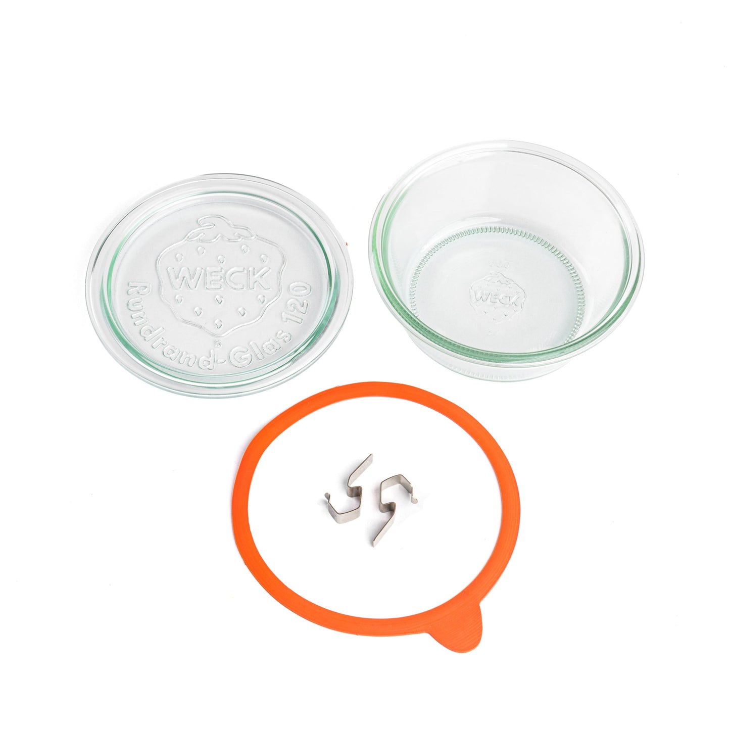 Разобранные части круглой стеклянной банки Weck: прозрачная крышка с гравировкой логотипа Weck, оранжевый силиконовый уплотнитель и металлические зажимы, на белом фоне.
