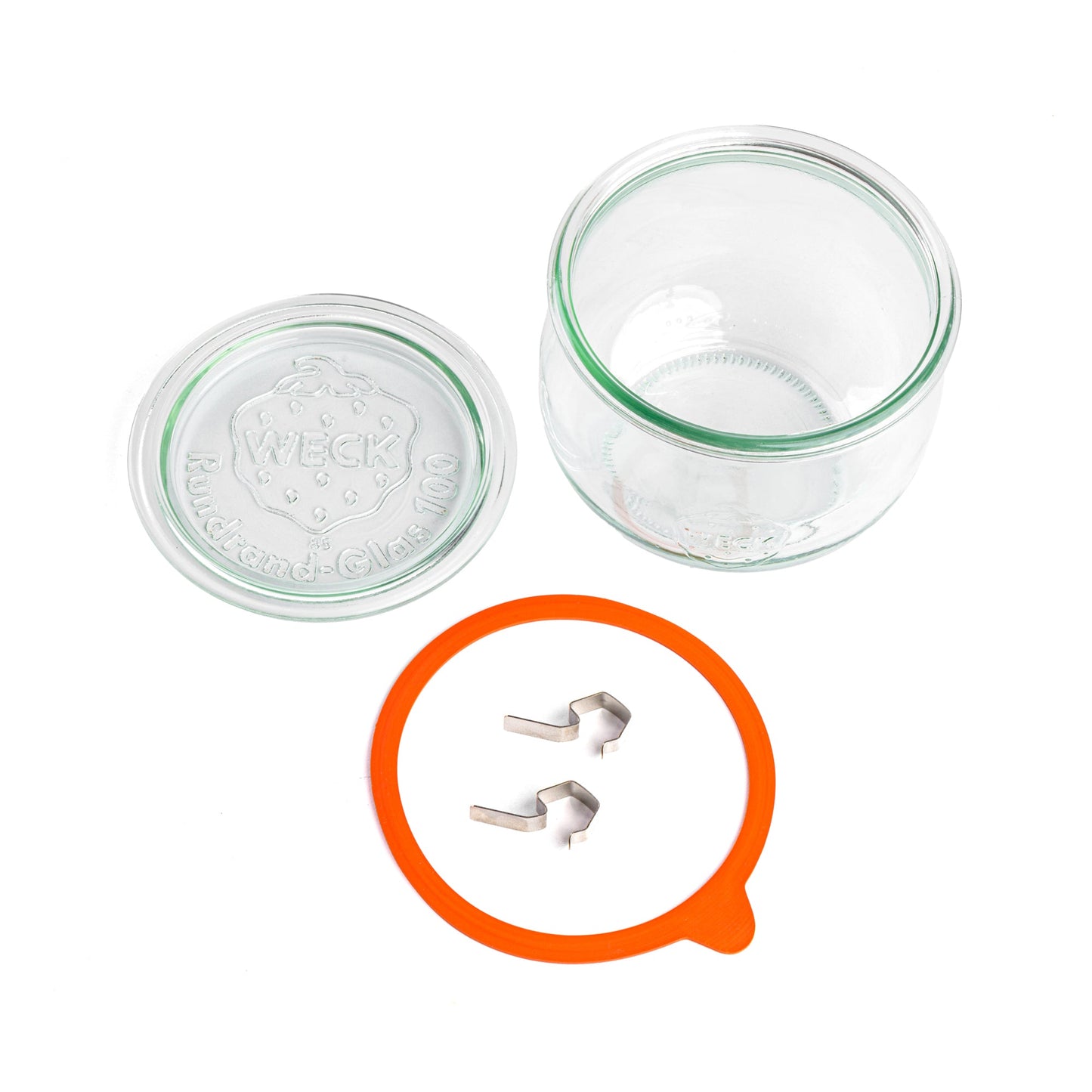 Разобранная стеклянная банка WECK, вид сверху: стеклянная банка без крышки, отдельно лежащая оранжевая уплотнительная резинка и две металлические застежки на белом фоне, крышка с гравировкой WECK и надписью 'Rundrand-Glas 100'.