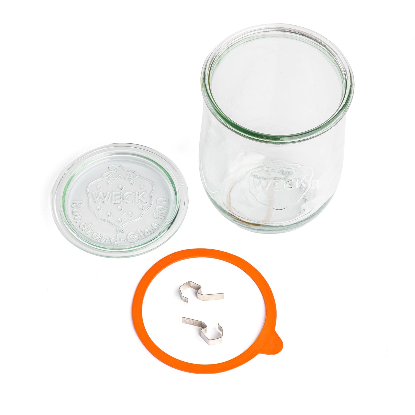 Разобранная стеклянная банка WECK: отдельная крышка с гравировкой WECK и 'Rundrand-Glas 100', оранжевая уплотнительная резинка и металлические зажимы, вид сверху