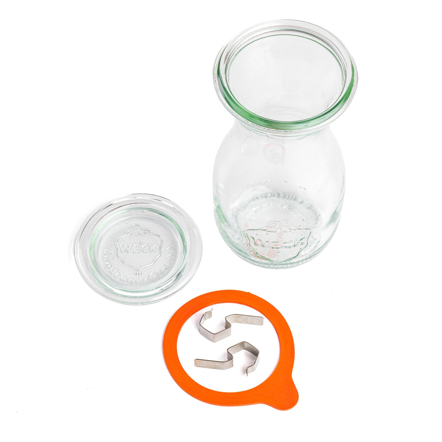 Разобранная стеклянная банка WECK с узким горлом и расширяющимся дном, вид сверху. Отдельно лежащая крышка с гравировкой WECK, оранжевая уплотнительная резинка и металлические зажимы, на белом фоне.
